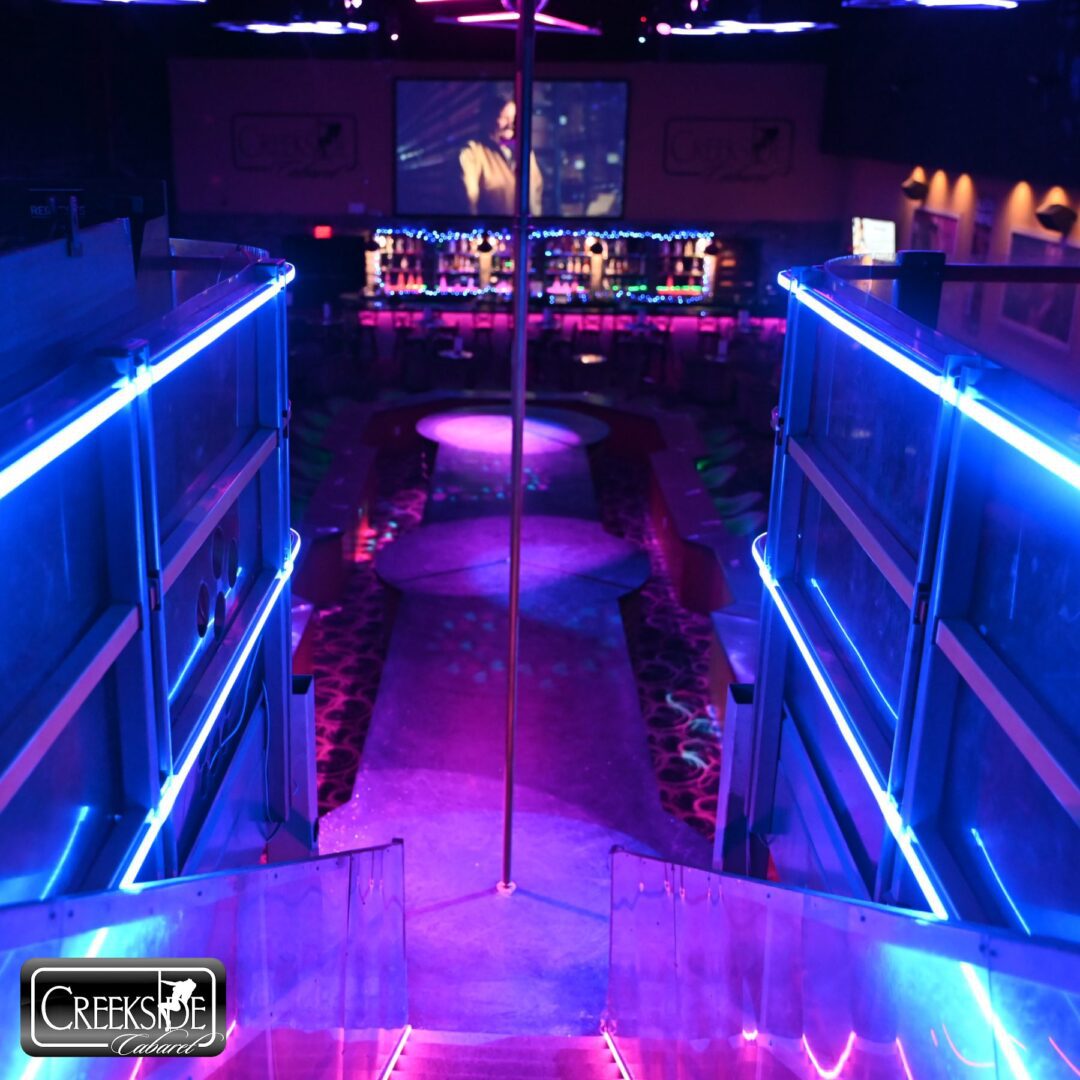 Neon-lit nightclub staircase with vibrant purple and blue lighting.