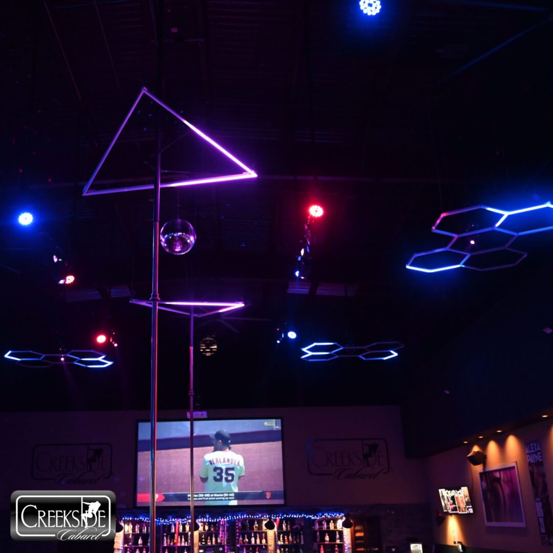 Neon-lit ceiling with geometric shapes and a vibrant bar ambiance.