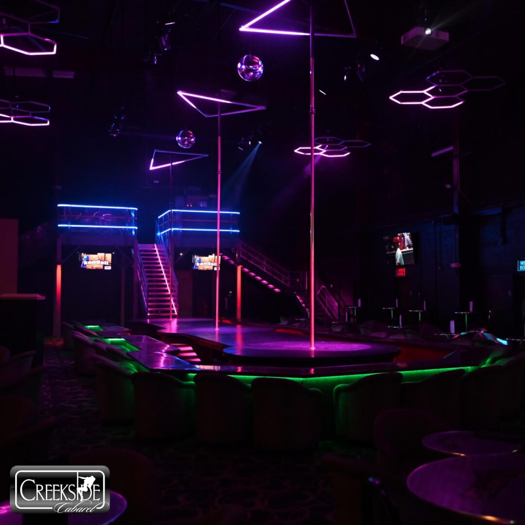 Empty nightclub with neon lights and poles for dancing.