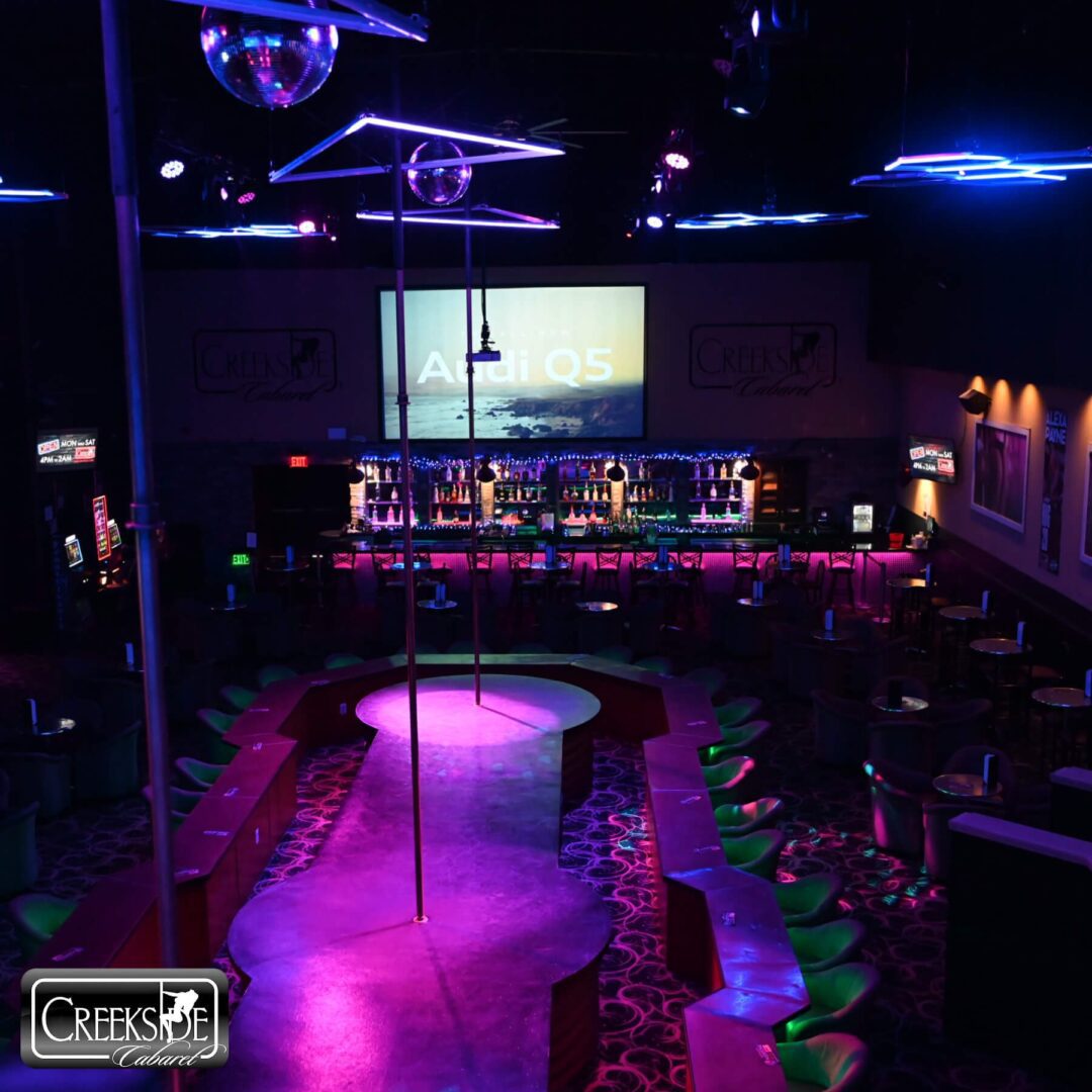 Dimly lit nightclub with neon lights and empty dance floor.